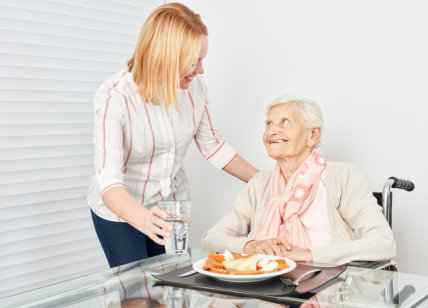 adult woman preparing meal for senior woman