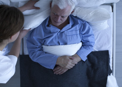 caregiver assisting senior man in bed